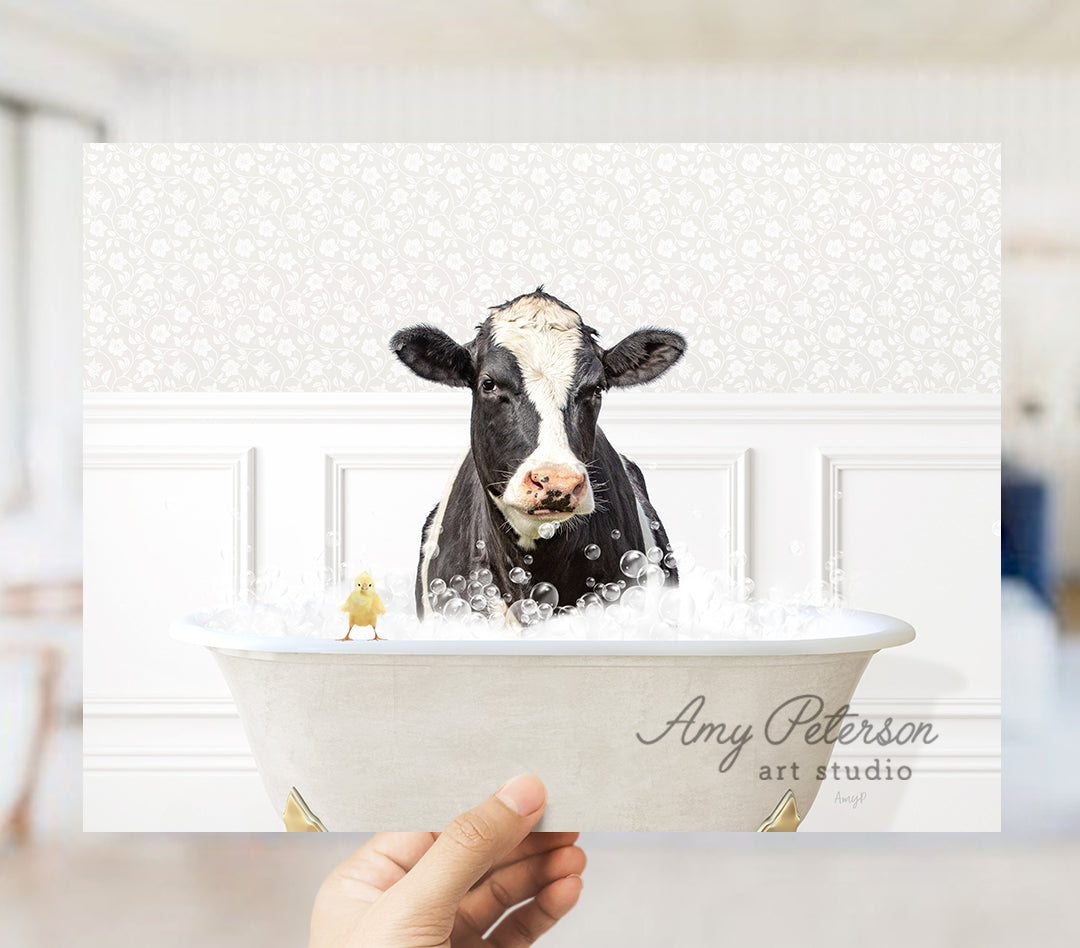 a person holding up a picture of a cow in a bathtub