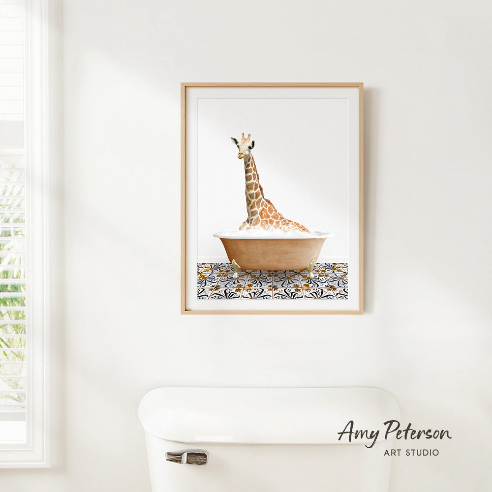 A framed print of a giraffe sitting in a bathtub is hanging on a white wall.