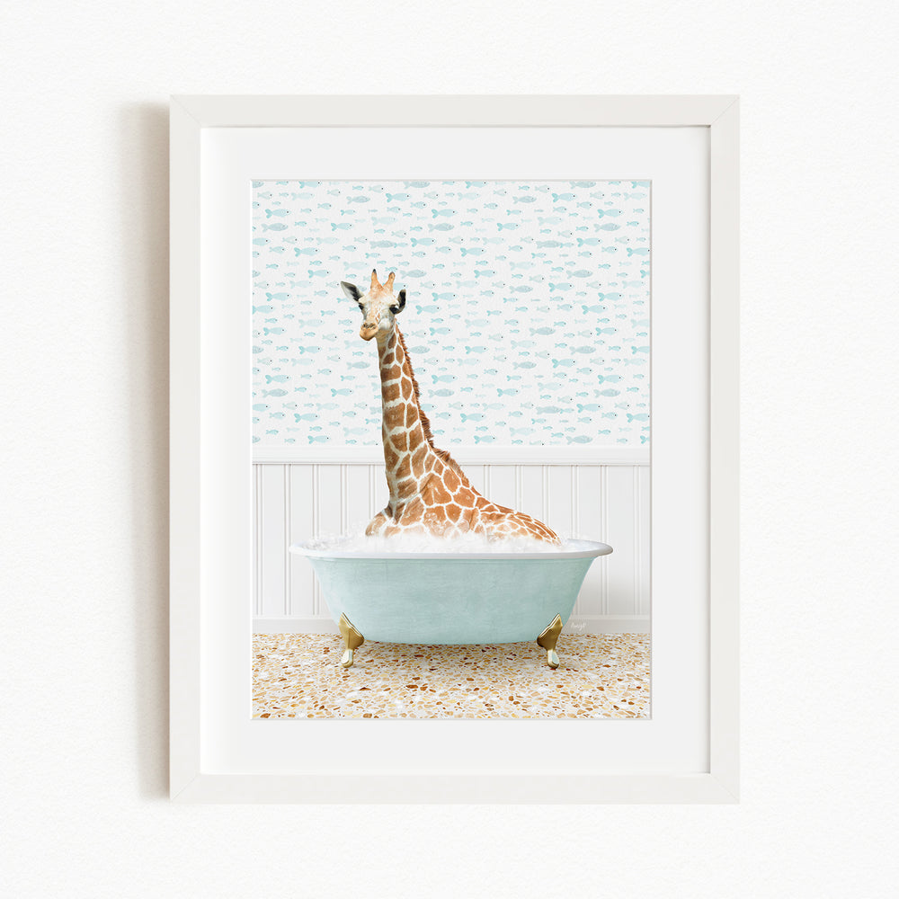 A giraffe is sitting in a light blue bathtub, surrounded by a patterned tile floor and a white wall with a blue and white fish wallpaper.