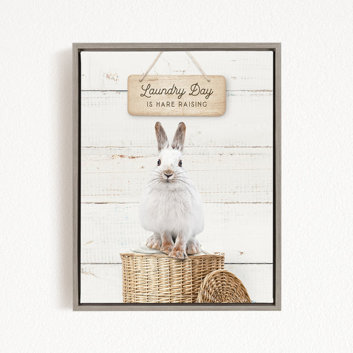 A white rabbit sitting in a woven basket, with a wooden sign above that says "Laundry Day is HARE RAISING".