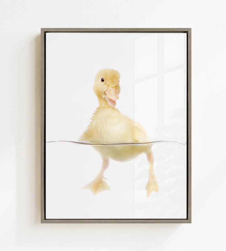 A cute yellow duckling swimming in water, with its head and feet visible above the water's surface.