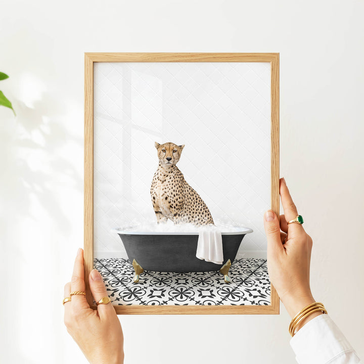 A person's hands are holding a framed picture of a cheetah sitting in a bathtub filled with water, creating a whimsical and playful scene.