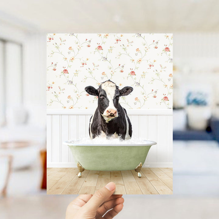 A black and white cow is sitting in a green bathtub filled with water, creating a whimsical and humorous scene.
