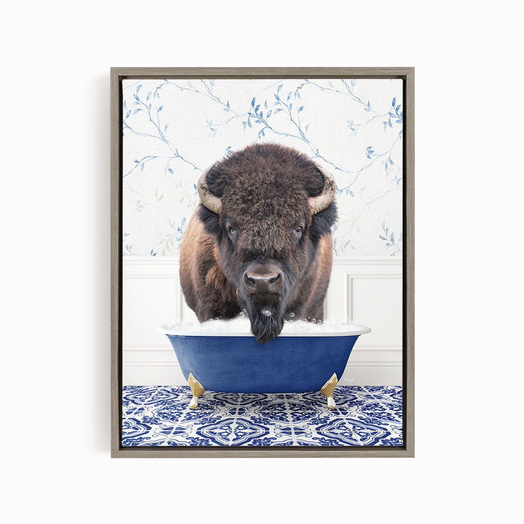 A buffalo with large horns is standing in a blue bathtub, with a patterned tile floor beneath it.