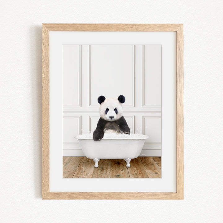 A panda bear sitting in a white bathtub, surrounded by a wooden floor and white walls.