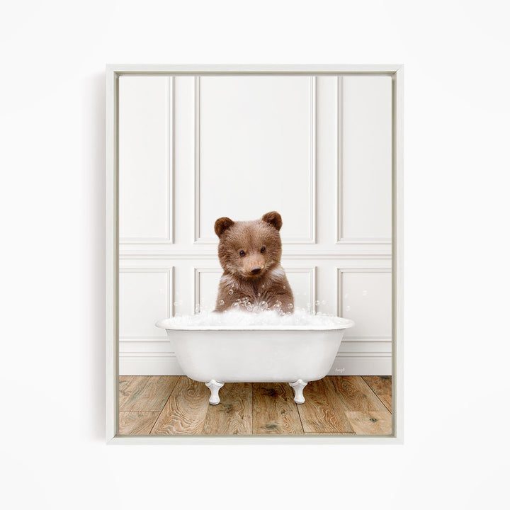 A brown bear sitting in a white bathtub filled with bubbles, looking directly at the camera.