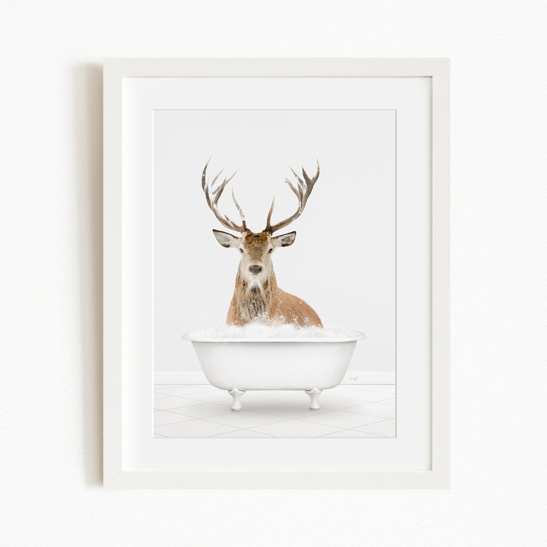 A deer with large antlers is sitting in a white bathtub filled with water, creating a whimsical and unexpected scene.