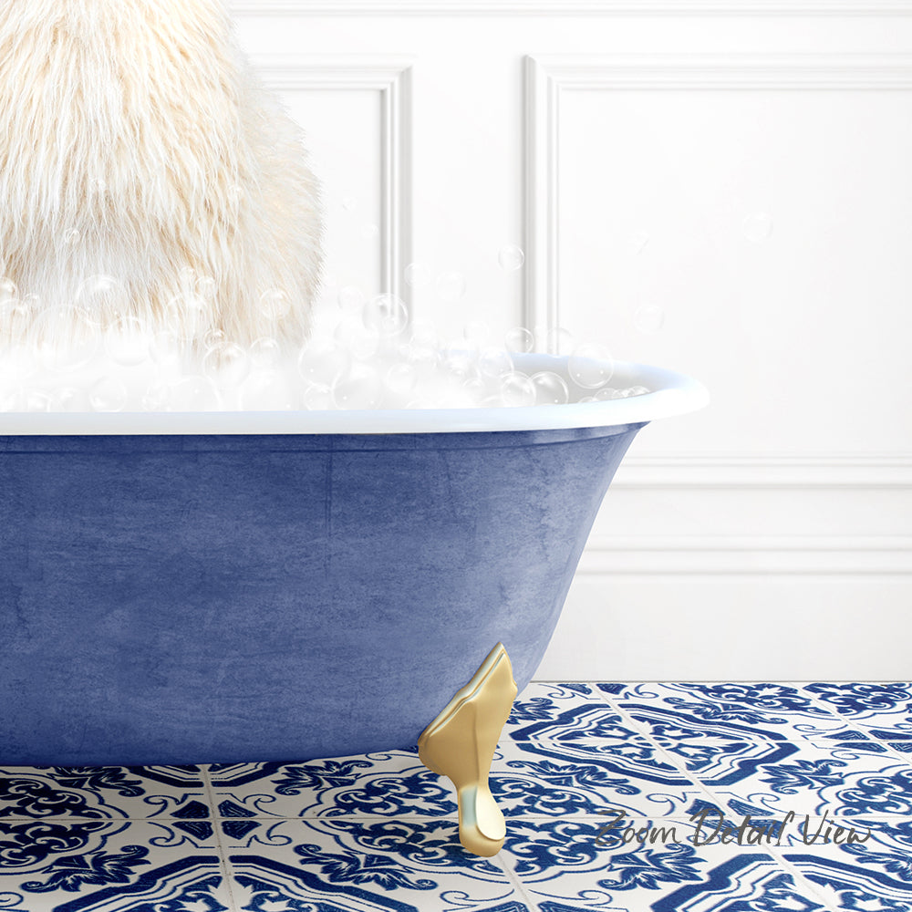 A fluffy white cat is sitting in a blue bathtub filled with bubbles, with a gold claw-like object on the floor.