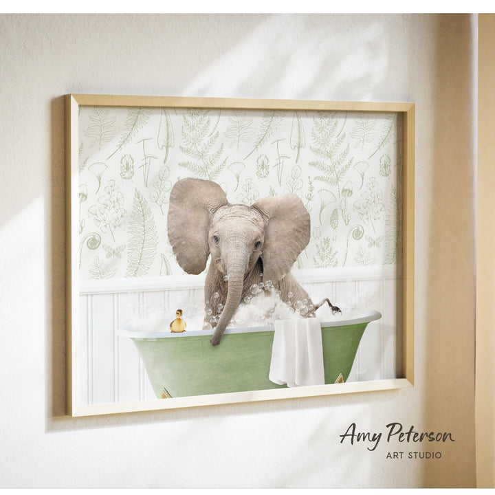 A framed image of an elephant sitting in a green bathtub, surrounded by bubbles and a yellow toy.
