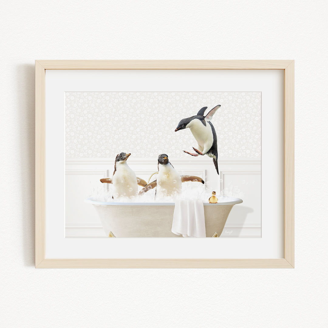 A framed image depicting three penguins enjoying a bath in a white bathtub, with one penguin flying above the tub.