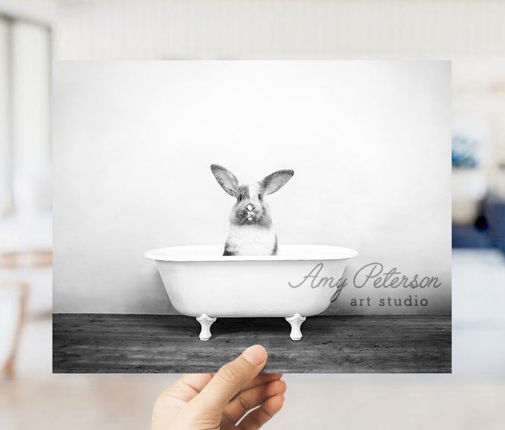 a person holding up a photo of a rabbit in a bathtub