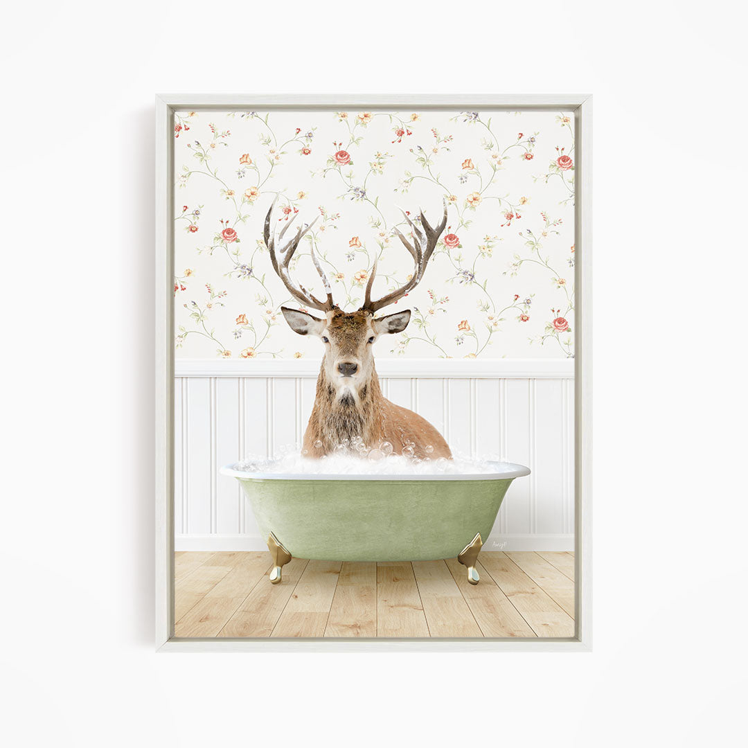 A deer with large antlers is sitting in a green bathtub filled with water, surrounded by a floral wallpaper.