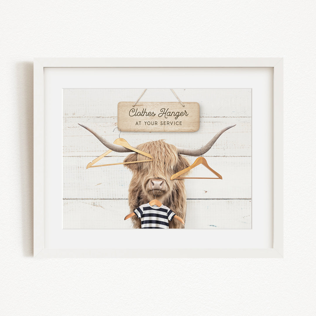 A framed image depicting a large, furry animal with a sign that reads "Clothes Hanger at your service" in front of it.