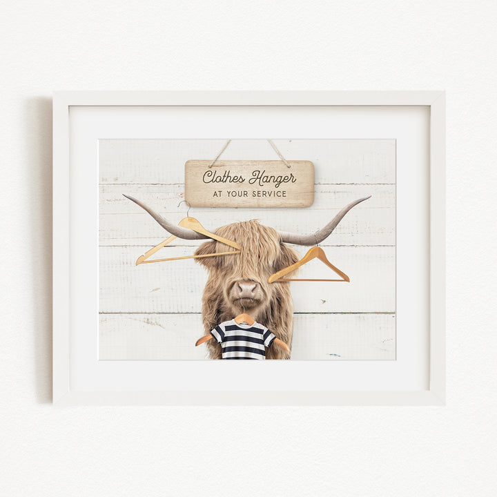 A framed image depicting a large, furry animal with a sign that reads "Clothes Hanger at your service" in front of it.