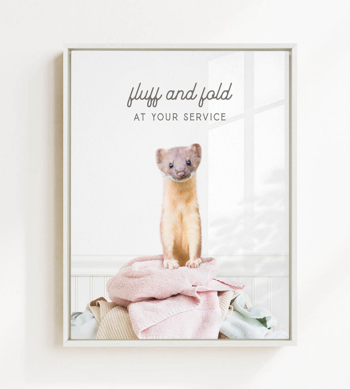 A small brown and white ferret standing on a pile of clothes, with the text "fluff and fold at your service" written above the image.