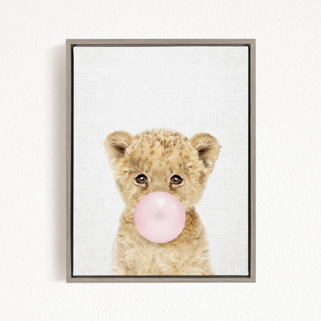 A cute baby lion blowing a bubble with a pink bubble gum bubble.