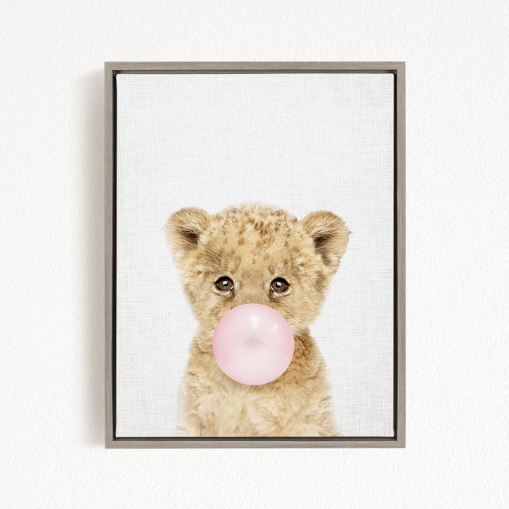 A cute baby lion blowing a bubble with a pink bubble gum bubble.
