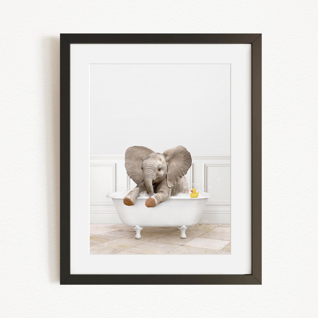 A baby elephant sitting in a white bathtub, with a yellow rubber duck floating nearby.