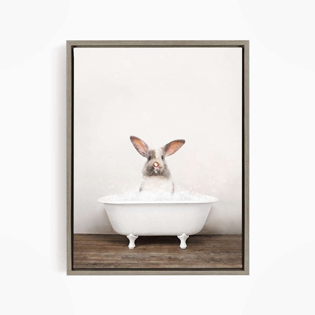 A white rabbit sitting in a white bathtub filled with bubbles, looking directly at the camera.