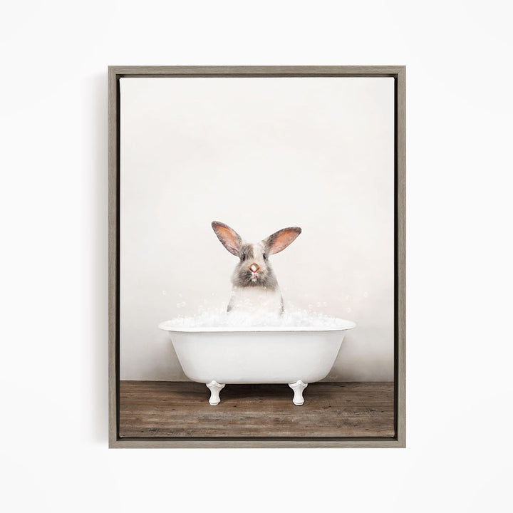 A white rabbit sitting in a white bathtub filled with bubbles, looking directly at the camera.