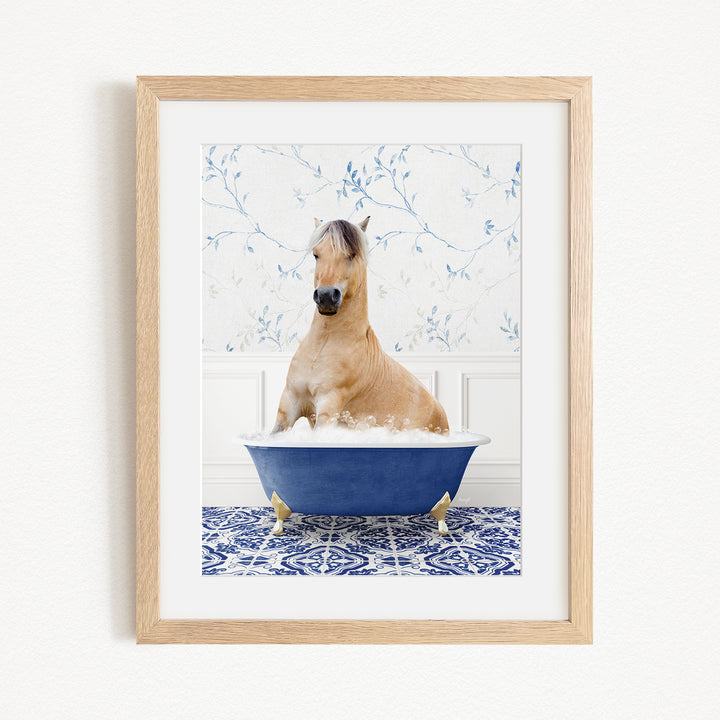 A light brown horse is sitting in a blue bathtub filled with water, surrounded by a blue and white patterned floor.