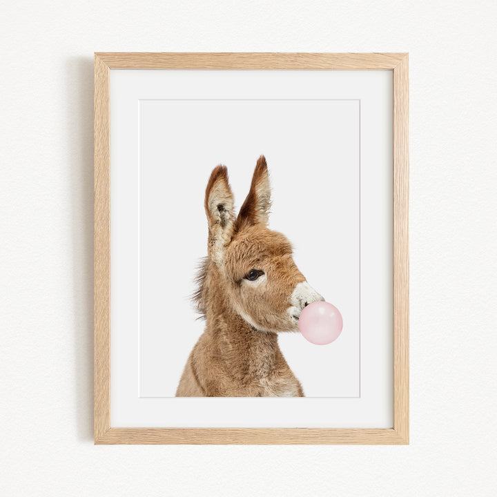 A picture of a donkey blowing a bubble with a pink bubble gum bubble.