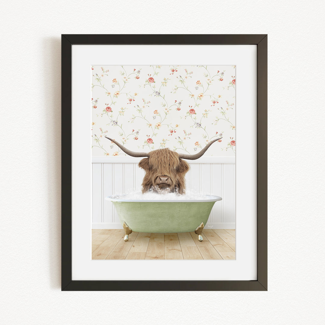 A framed image depicting a Highland cow with long horns sitting in a green bathtub, surrounded by a floral wallpaper.