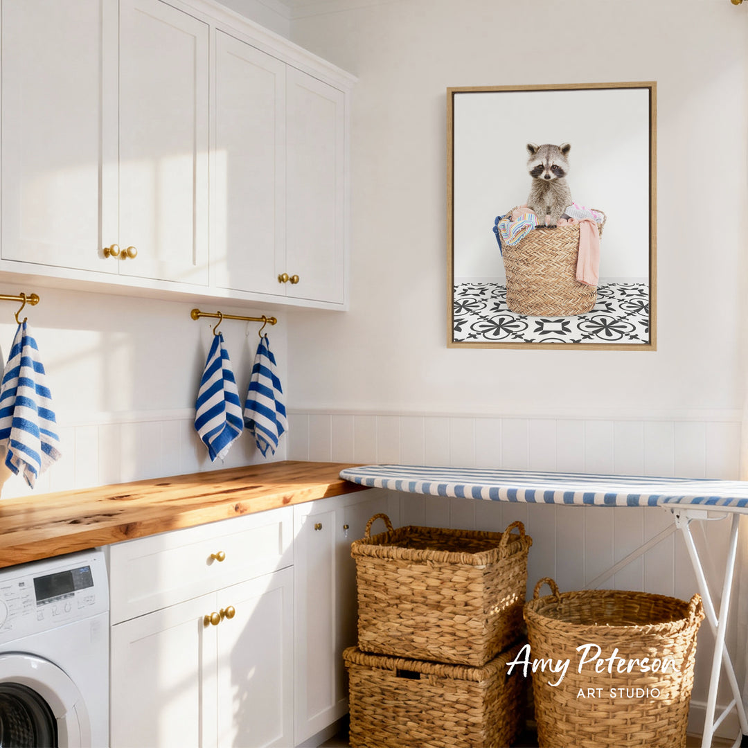 A laundry room with white cabinets, a wooden countertop, and a framed image of a raccoon in a basket.