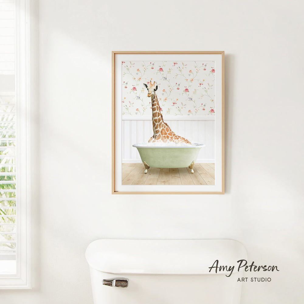 A framed print of a giraffe sitting in a bathtub is hanging on a white wall in a bathroom.