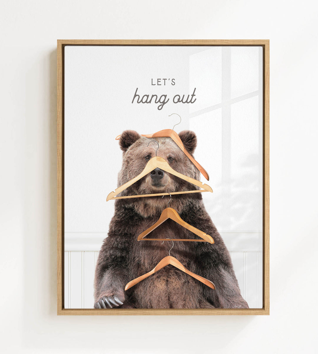 A framed image of a bear sitting on a shelf with multiple wooden hangers hanging from its head and neck.
