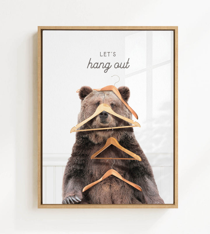 A framed image of a bear sitting on a shelf with multiple wooden hangers hanging from its head and neck.