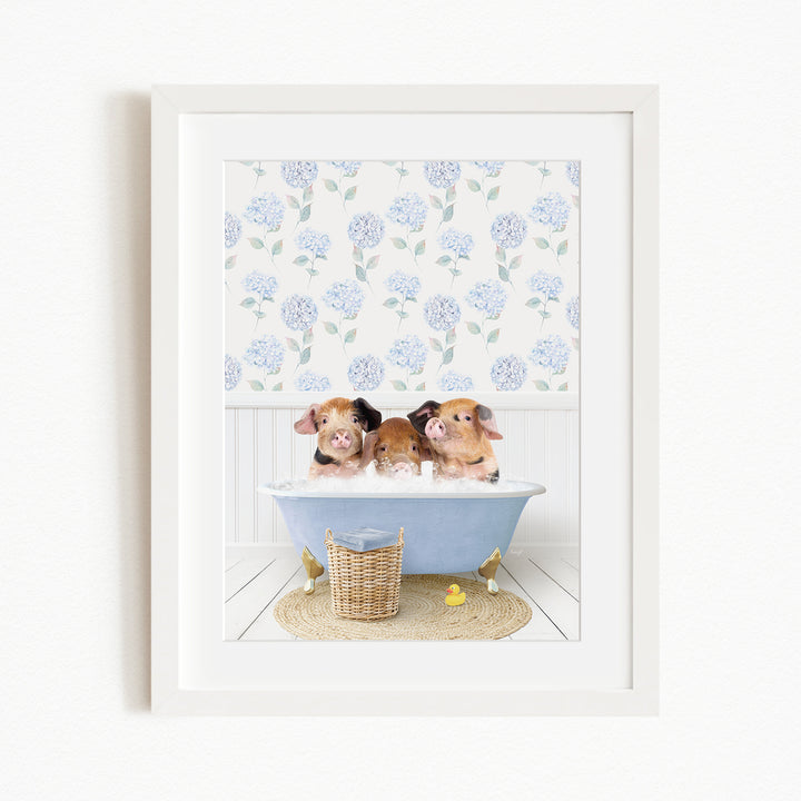 Three adorable pigs sitting in a blue bathtub, surrounded by a floral patterned wall and a basket of rubber ducks.