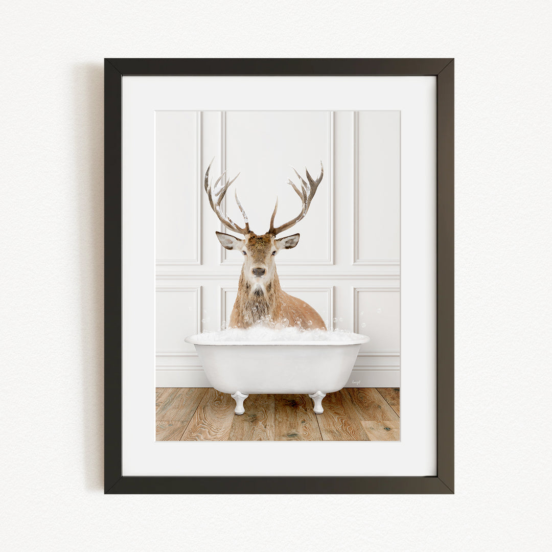 A deer with large antlers is sitting in a white bathtub filled with water, creating a whimsical and unexpected scene.