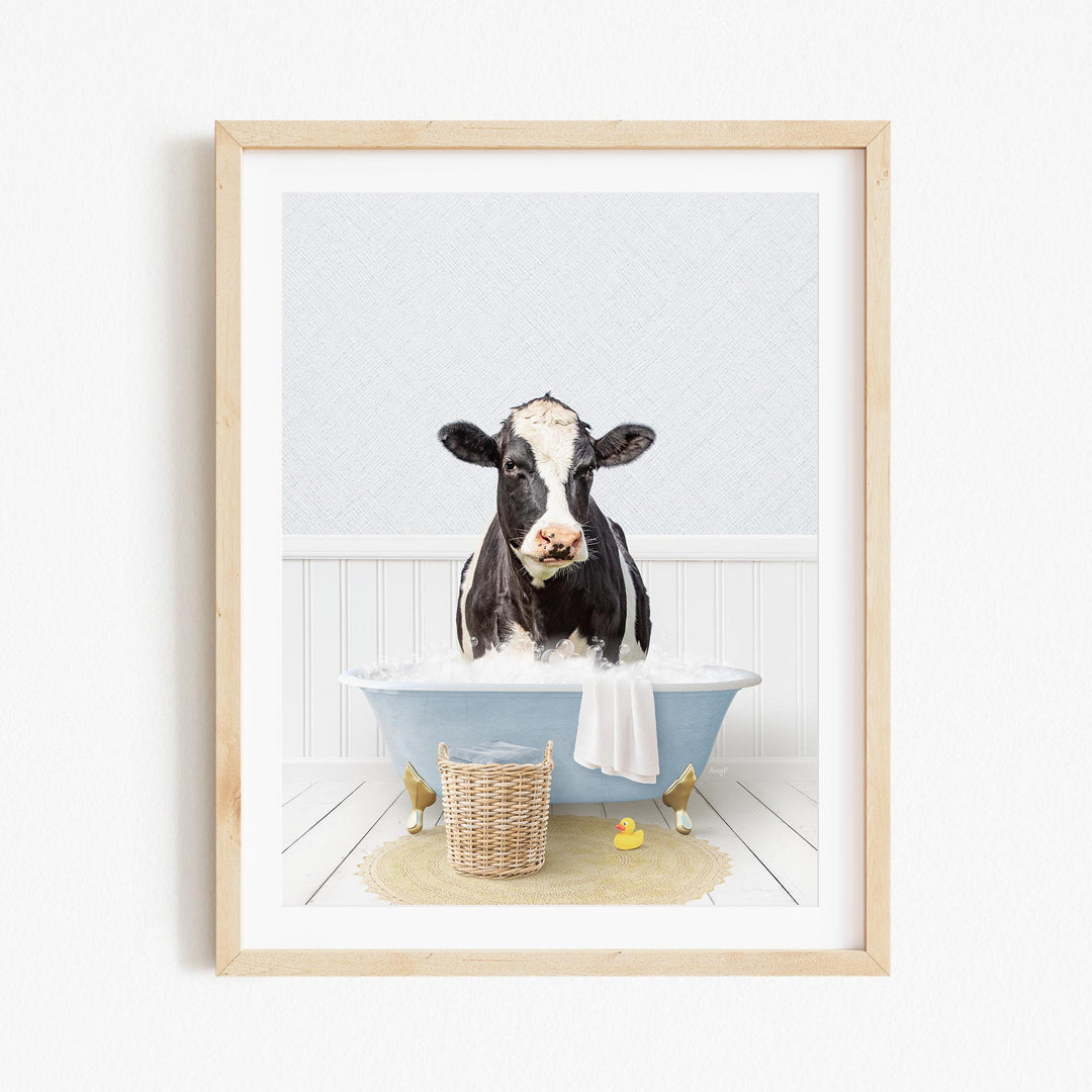 A black and white cow is sitting in a blue bathtub filled with water, surrounded by rubber ducks and a basket.
