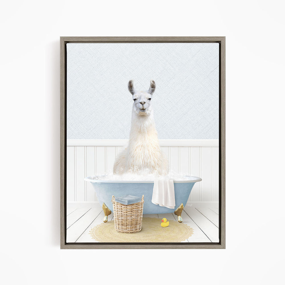 A white llama sitting in a blue bathtub filled with bubbles, surrounded by a basket of toys and a yellow rubber duck.