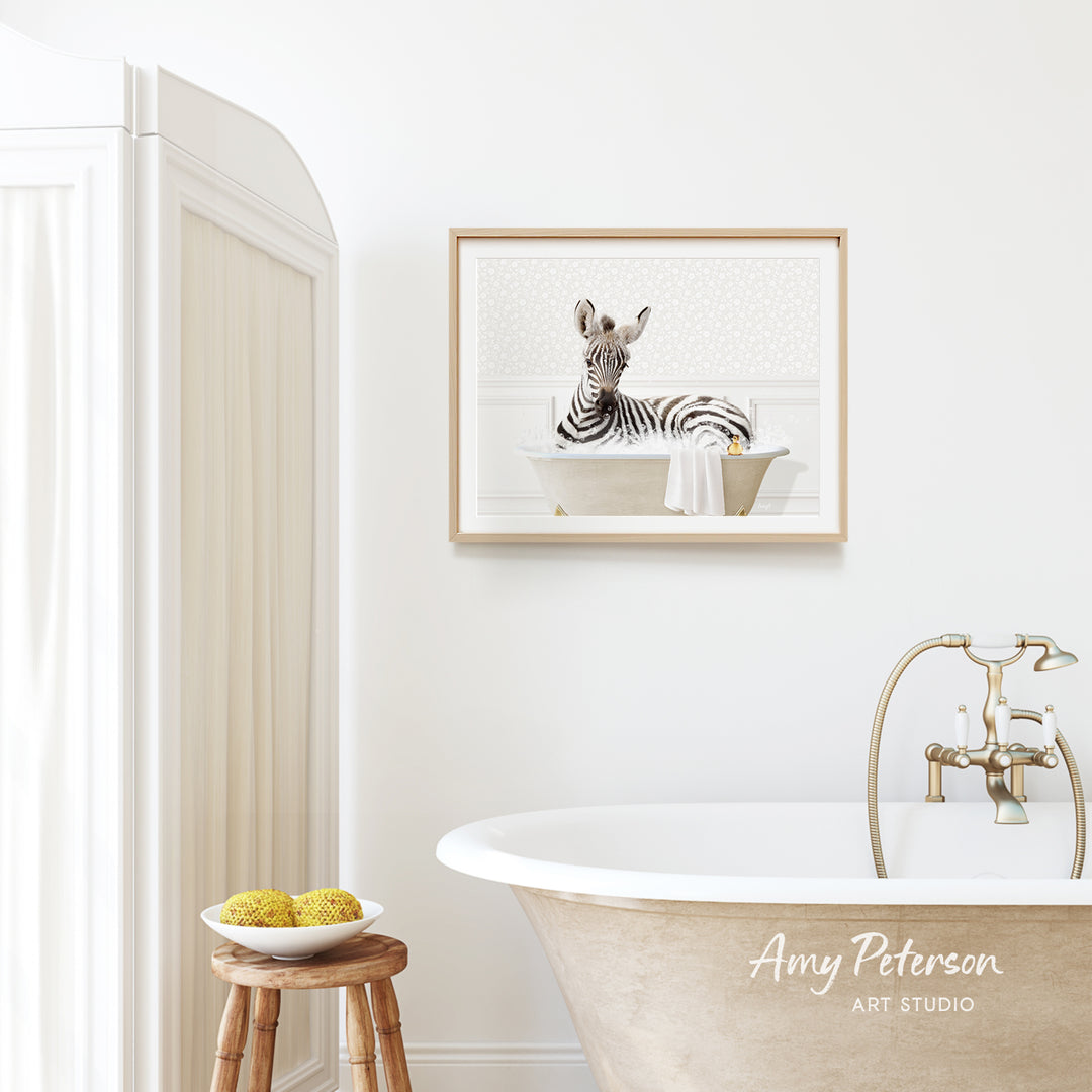a zebra sitting in a bathtub, with a framed picture of the zebra hanging on the wall above the bathtub.