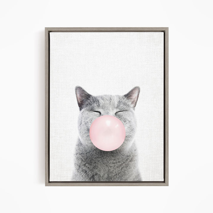 A gray cat blowing a pink bubble with its mouth.