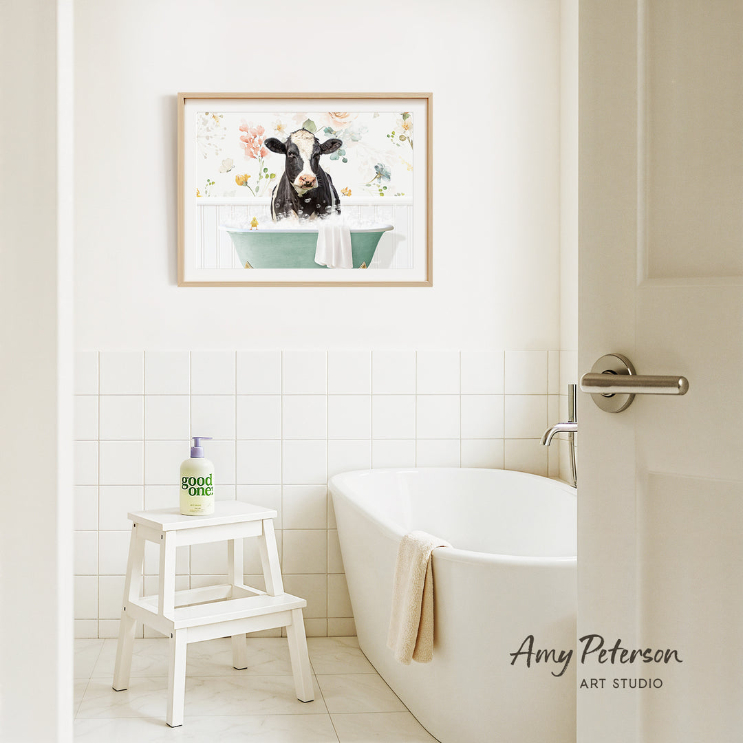 a bathroom with a white bathtub, a stool, and a framed picture of a cow in a bathtub hanging on the wall.