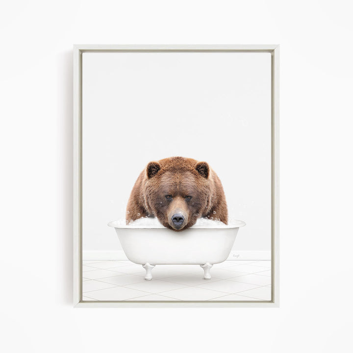 A brown bear is sitting in a white bathtub filled with water, appearing to enjoy the bath.