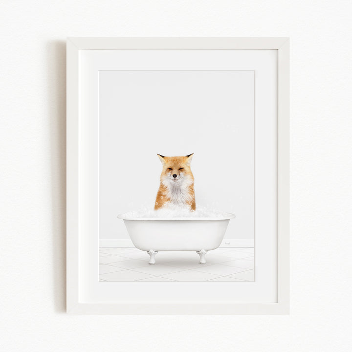A red fox is sitting in a white bathtub filled with bubbles, looking directly at the camera.