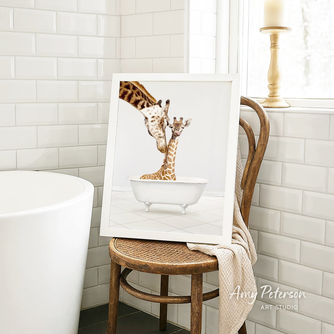 A framed photograph of two giraffes sitting in a bathtub, with one giraffe appearing to be feeding the other.