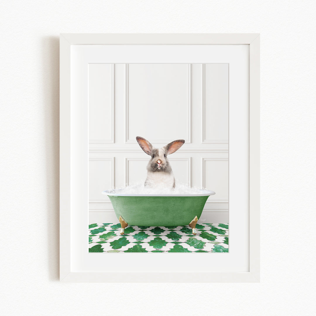 A white rabbit sitting in a green bathtub filled with bubbles, with a patterned green and white rug on the floor.
