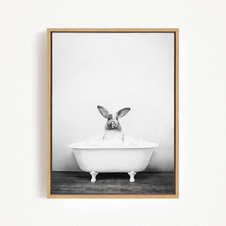 A black and white photograph of a rabbit sitting in a bathtub filled with water, looking up at the camera.