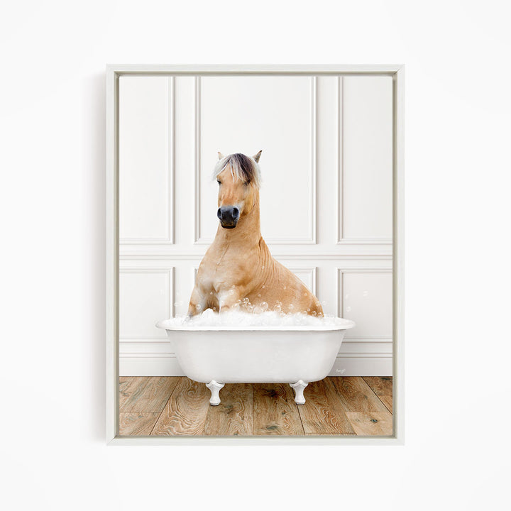 A brown horse sitting in a white bathtub filled with bubbles, with a white wall and wooden floor in the background.