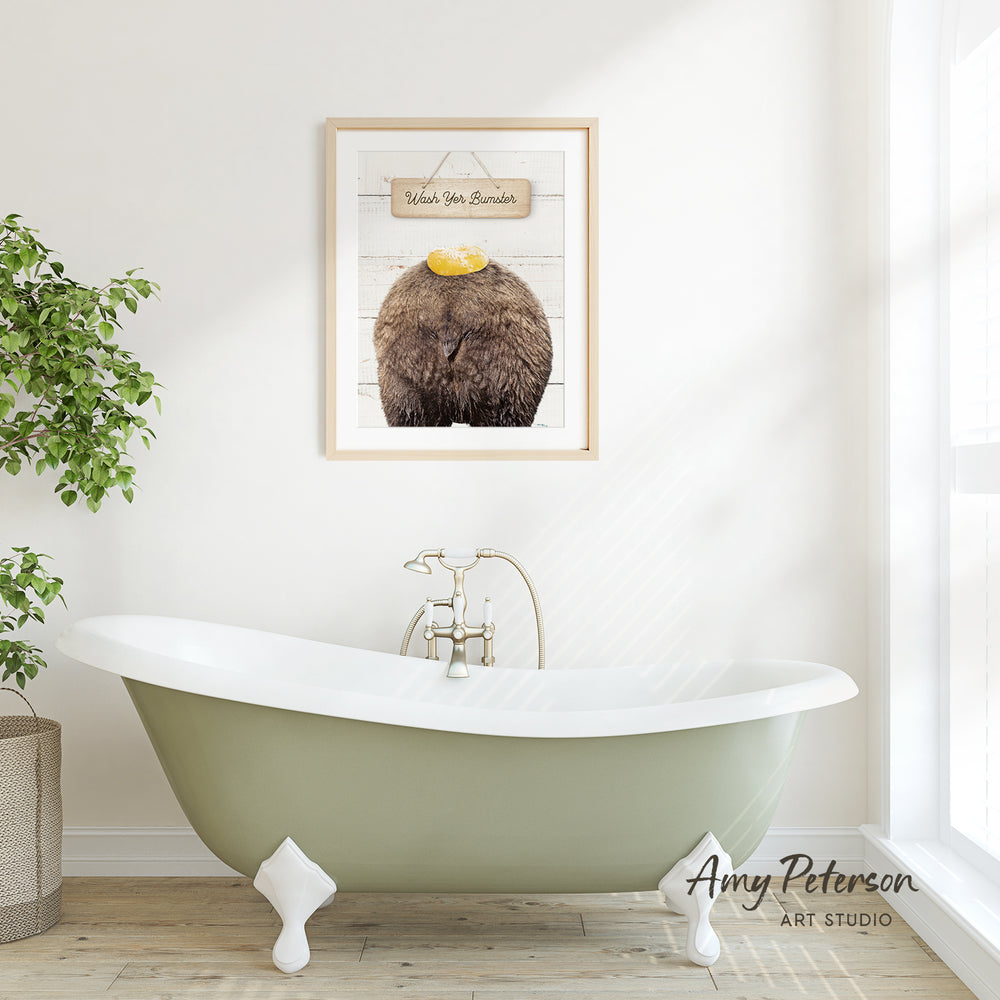 a green clawfoot bathtub with a framed picture of a bear above it, hanging on a white wall.
