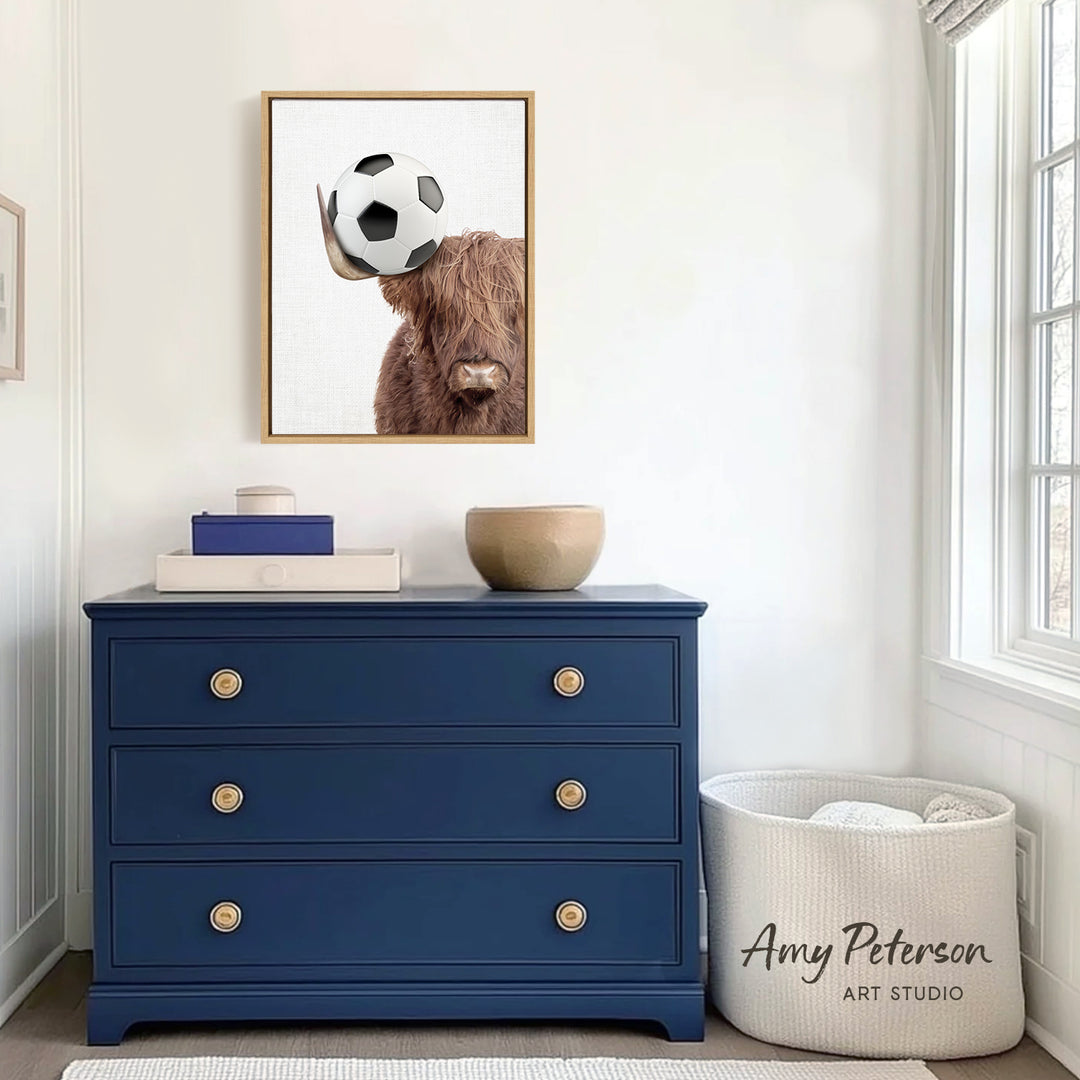 a blue dresser with a framed picture of a cow, a white basket, and a small bowl on top. The dresser is situated in a room with a window and a white wall.
