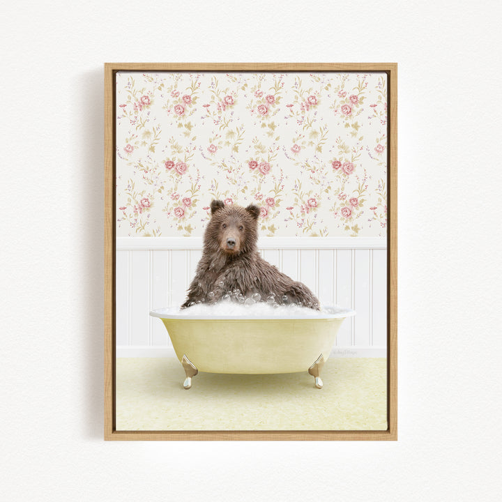 A brown bear sitting in a yellow bathtub filled with bubbles, surrounded by a floral wallpaper.