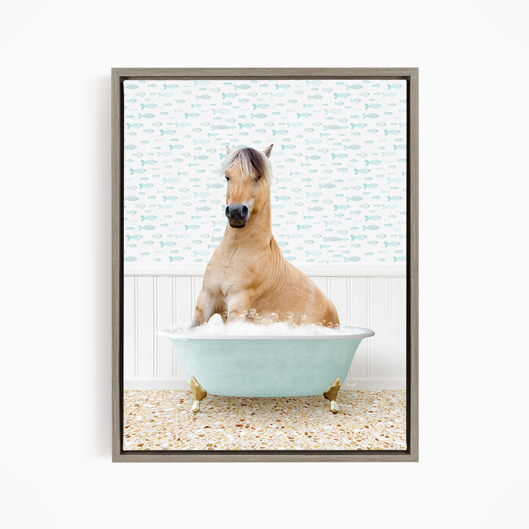 A light brown horse is sitting in a blue bathtub filled with water, surrounded by a pattern of small fish on the wall behind it.