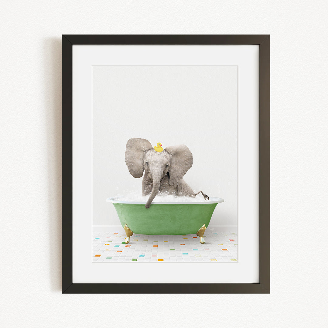 A gray elephant is sitting in a green bathtub filled with bubbles, with a yellow rubber duck floating on the water.