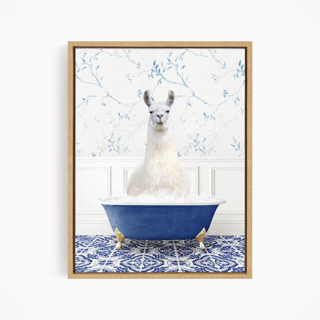 A white llama sitting in a blue bathtub filled with bubbles, with a blue and white floral patterned wall behind it.